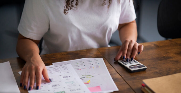 Empresária calculando tributos e analisando gráficos sobre tributação monofásica